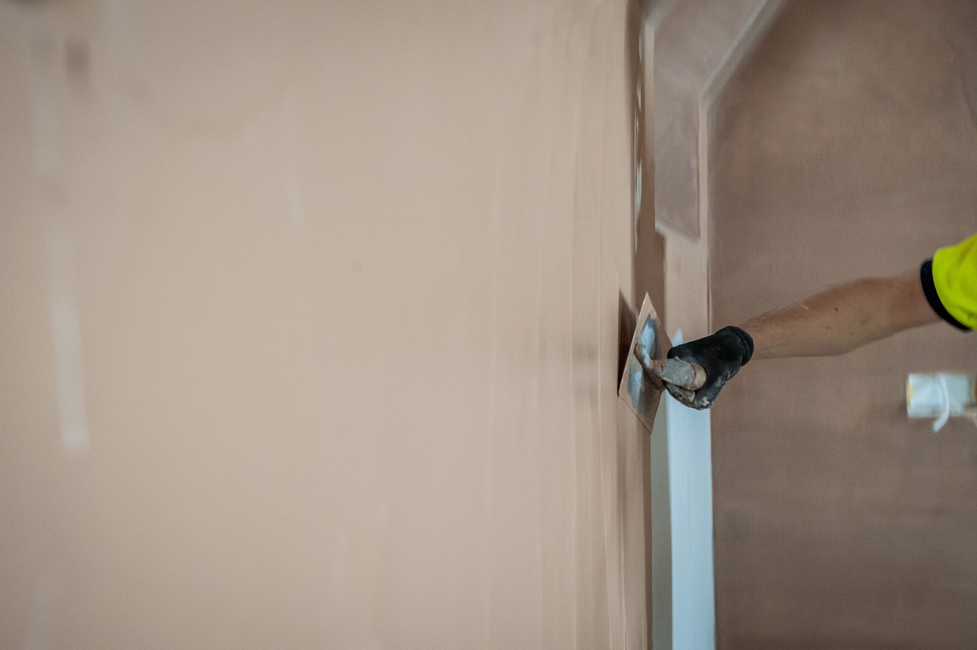 Photo of plasterer using a Float to smoothly finish a coat of plaster on a wall.
