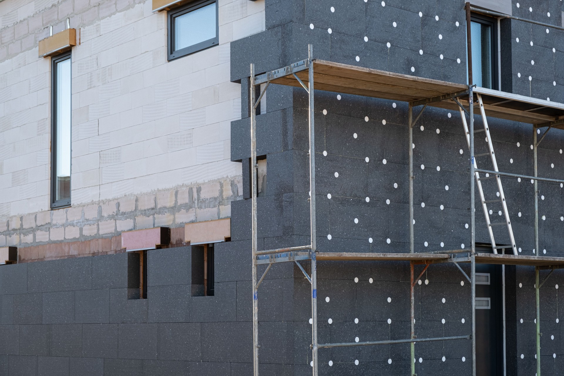 New House building in process insulation of the wall of the house with layers of modern thermal insulation materials . Exterior covering in construction site.